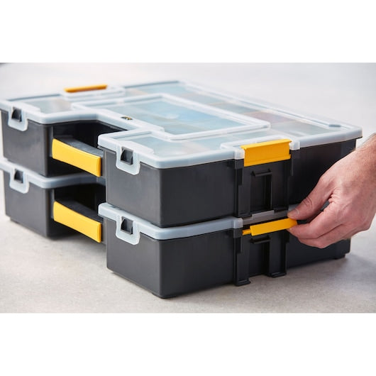 STANLEY 1-94-745 stackable black and yellow organizers with clear lids, close-up side angle, hand adjusting latch.