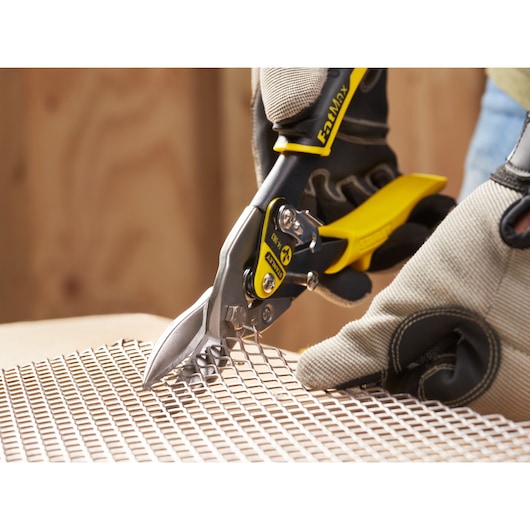 STANLEY 2-14-563 aviation snips cutting metal mesh, close-up with gloved hand holding tool.
