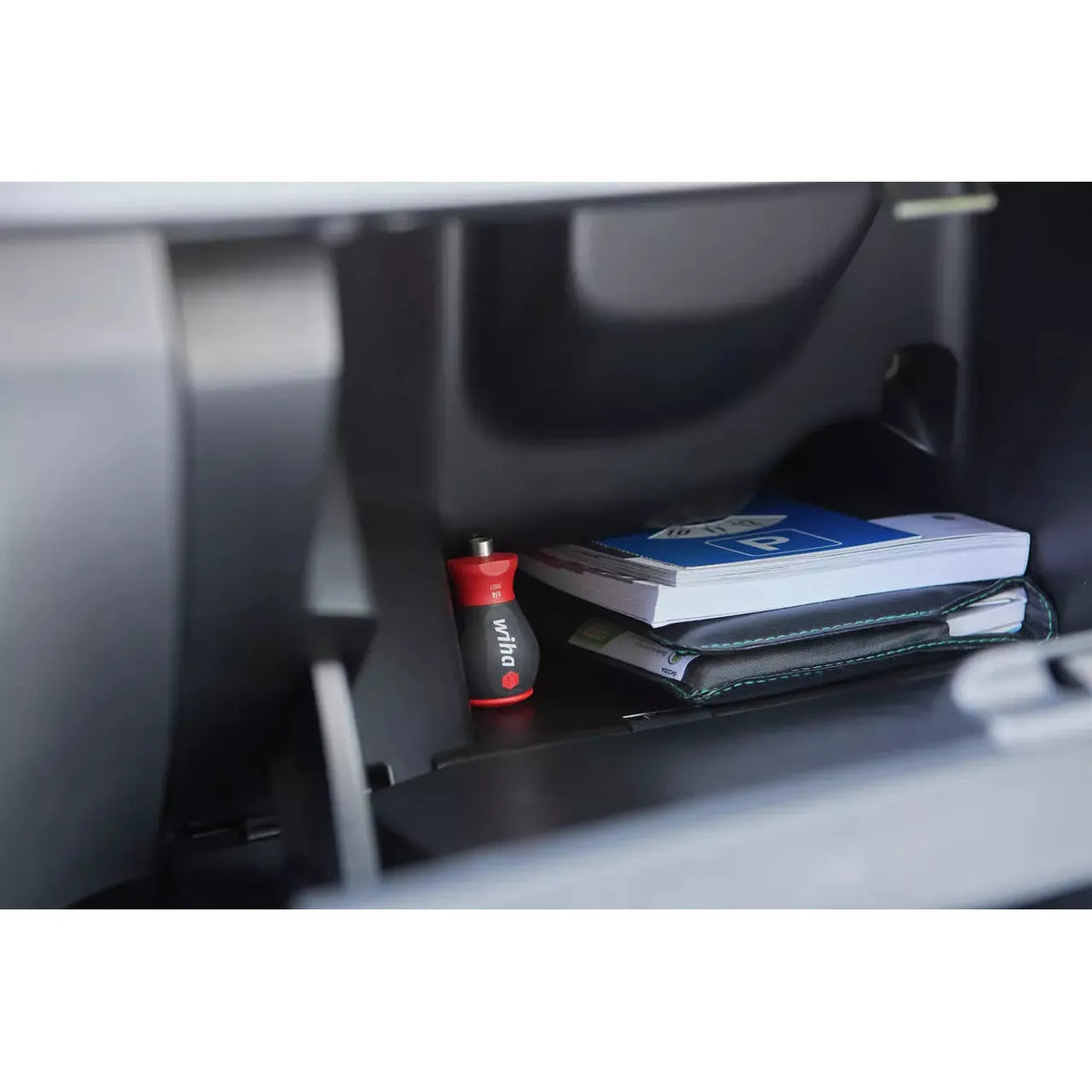 Phillips & Pozidriv – Red and black screwdriver in a glovebox with a book and a folder.