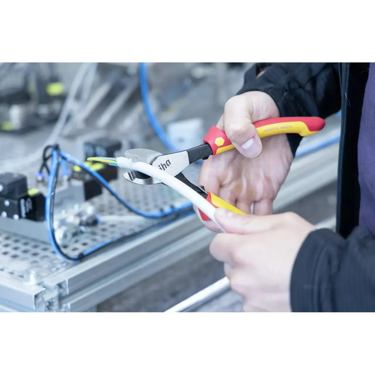 Person using industrial electric cable cutter on white cable