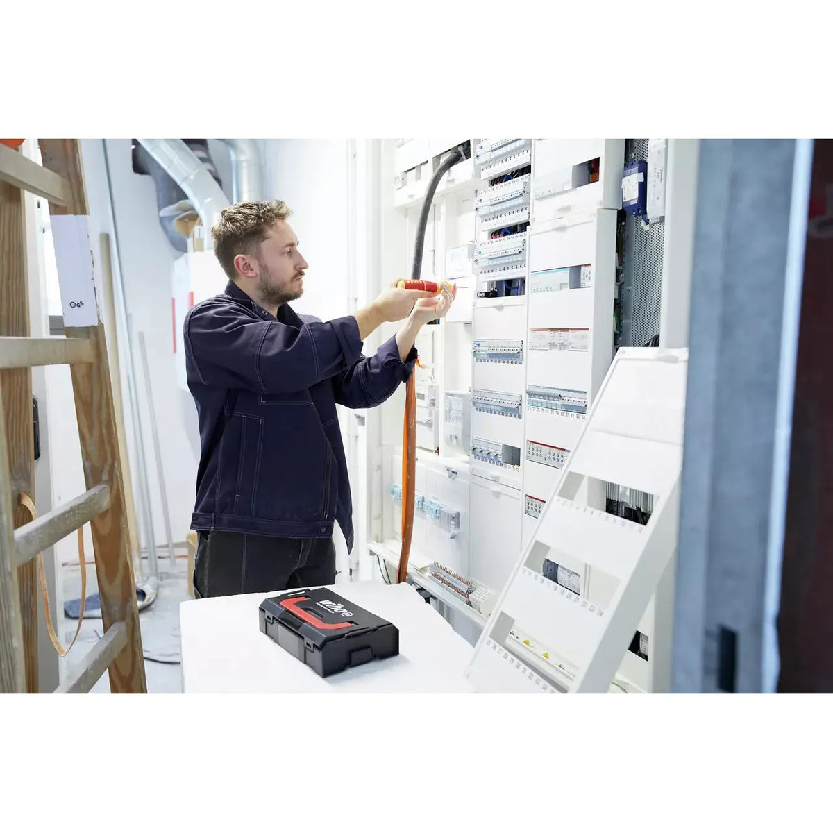 Man working with electric screwdriver on a control cabinet