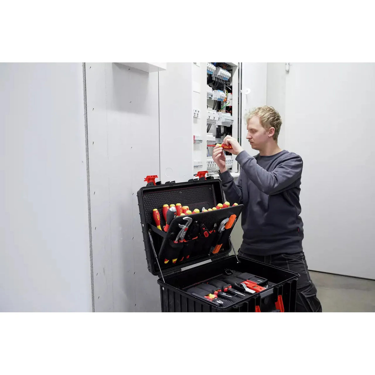 Person working on electrical panel with tool case open