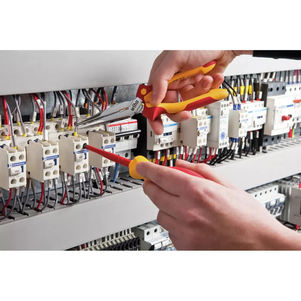 Person using pliers and screwdriver on electrical panel