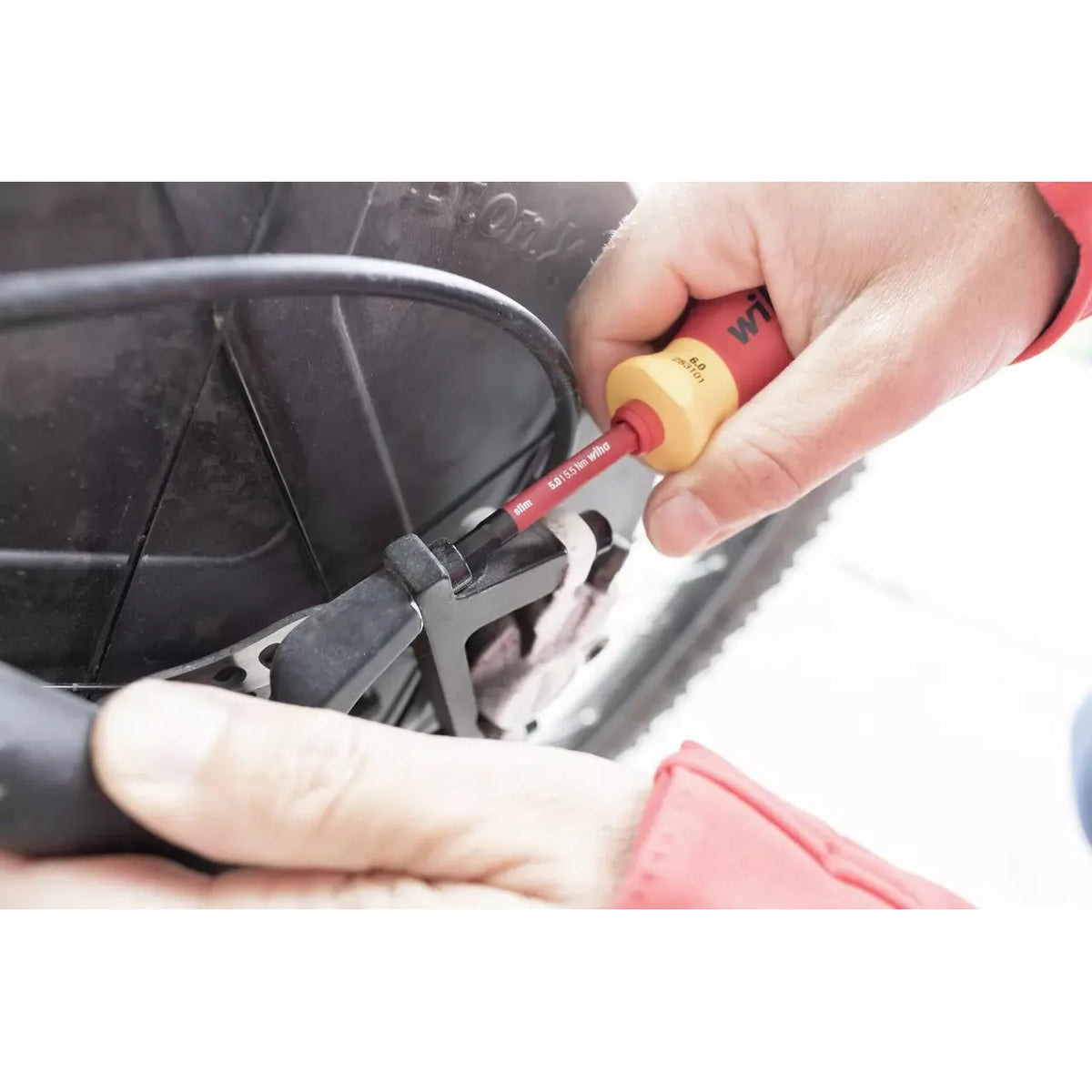 Person using an electric screwdriver to adjust a bicycle brake cable.