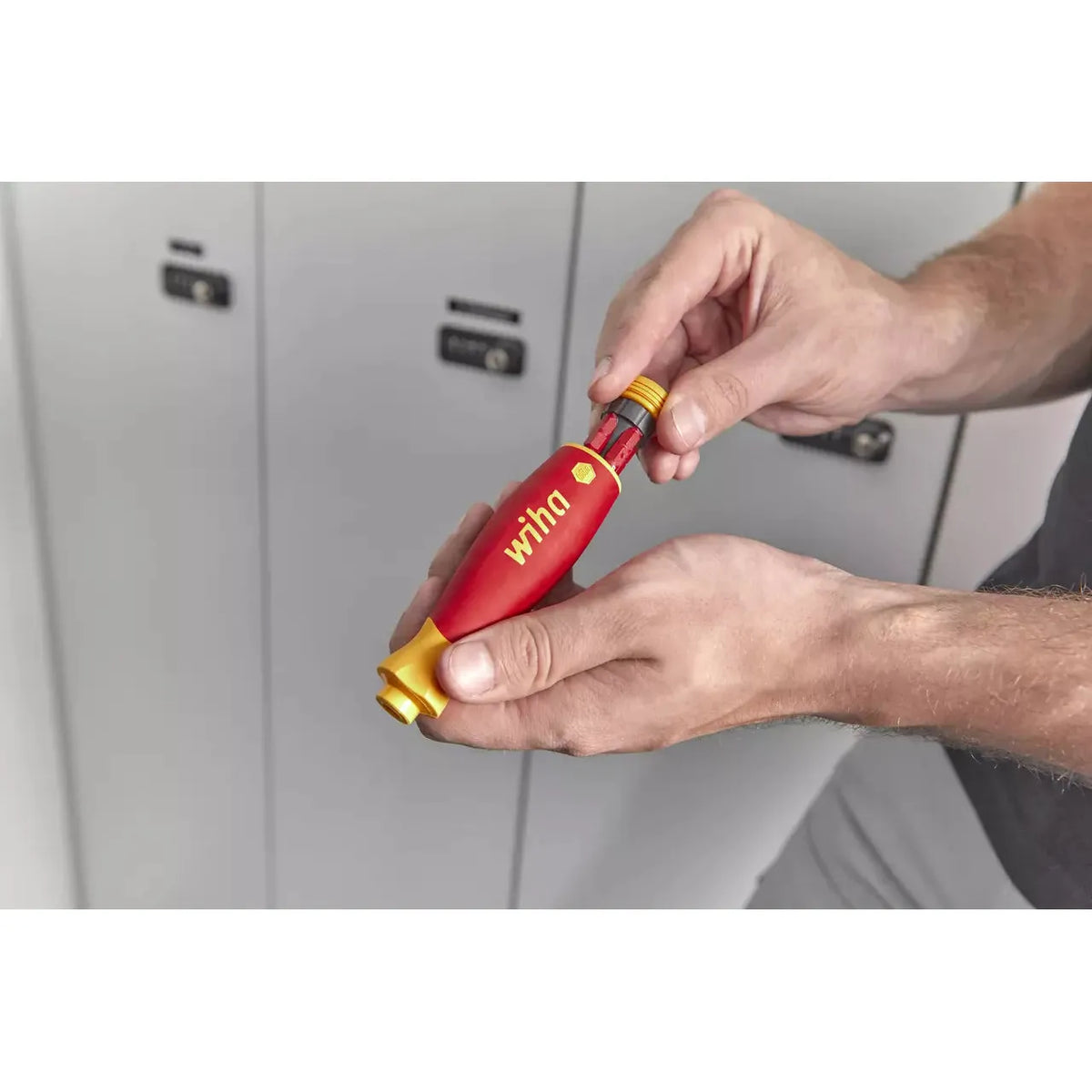 Person holding a red and yellow electric screwdriver with a bit magazine