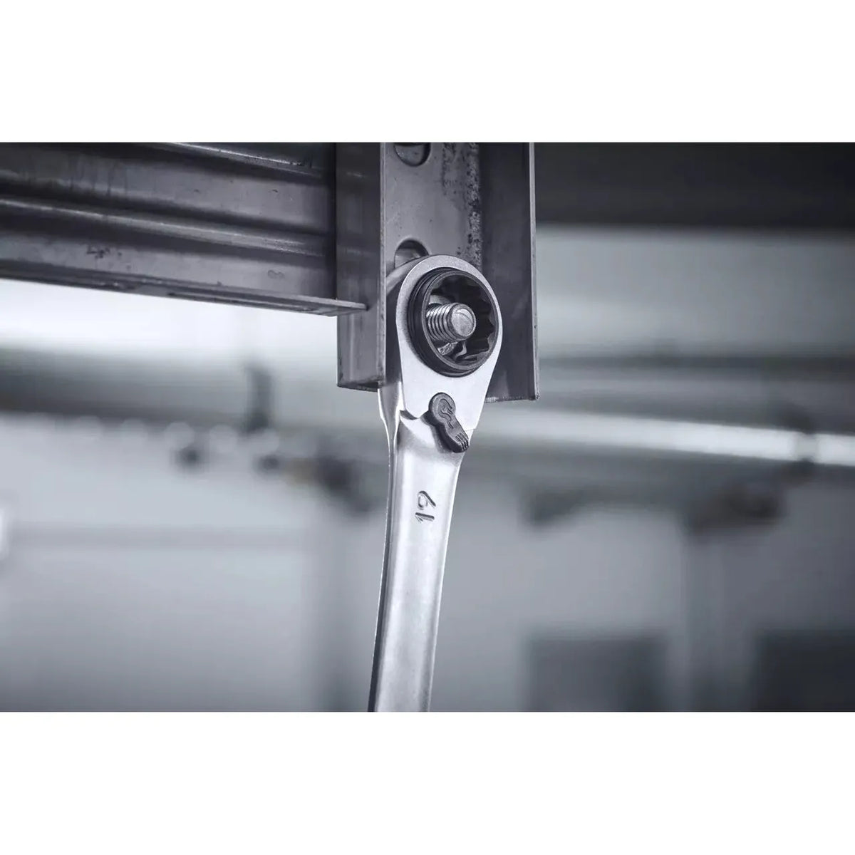 A ratchet wrench tightening a bolt on a metal structure.