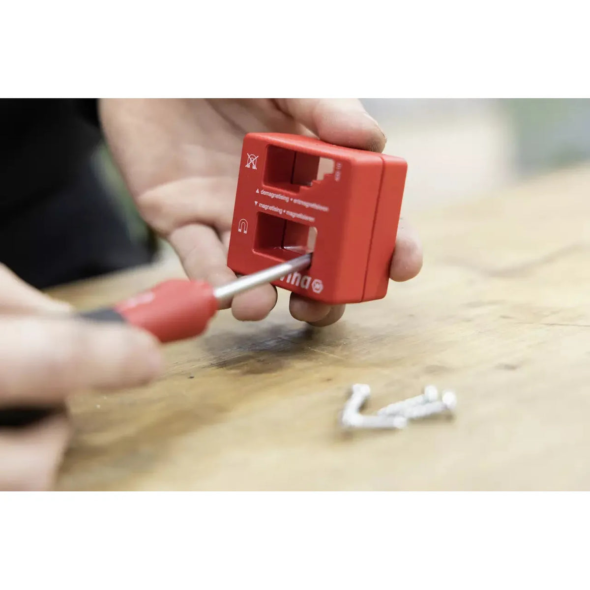 Person using a red magnetizer on a screwdriver tip