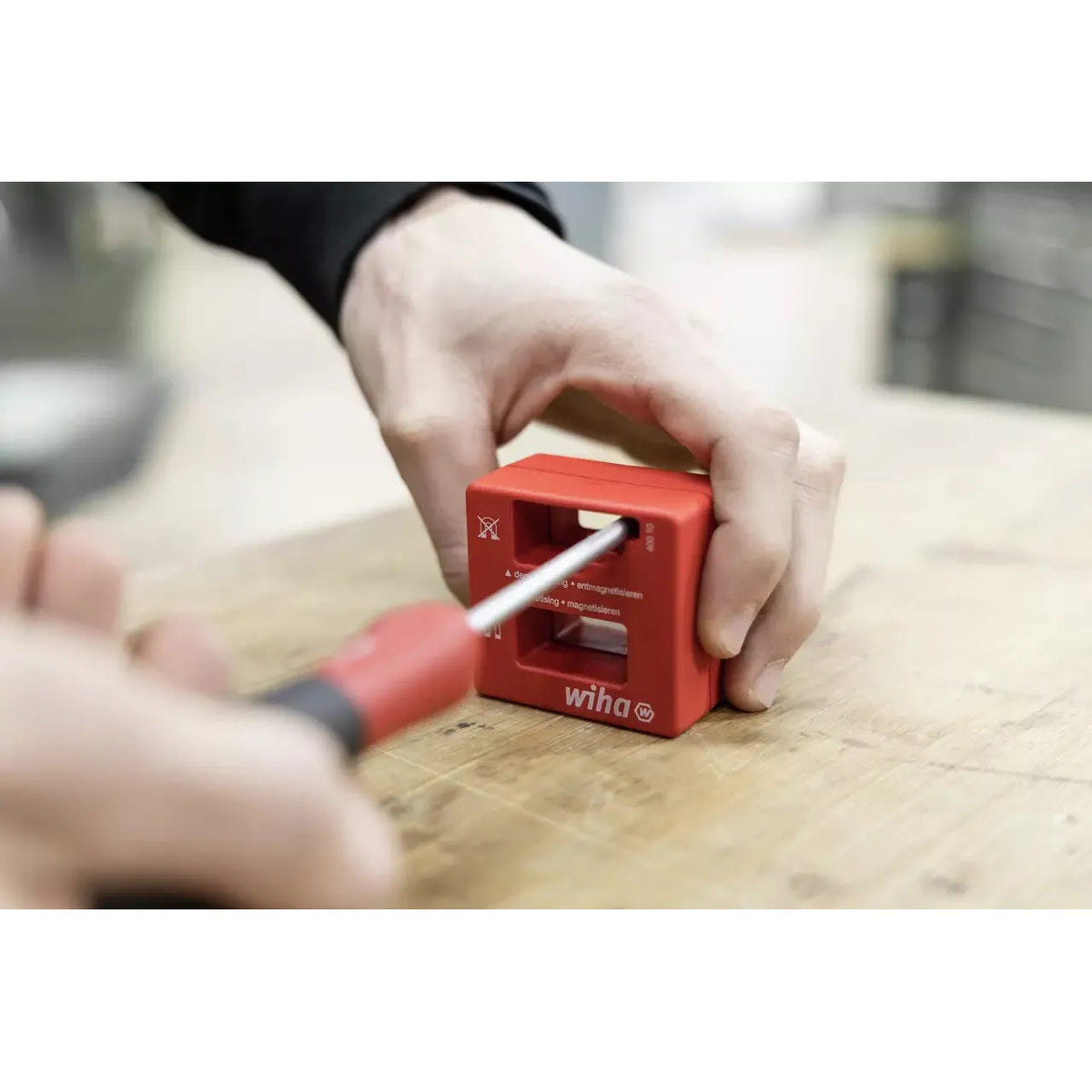 Hand using red magnetizer on screwdriver