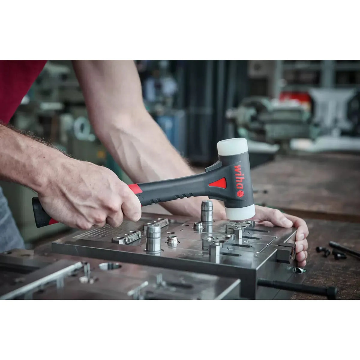 Person using rubber mallet on metal workpiece in workshop