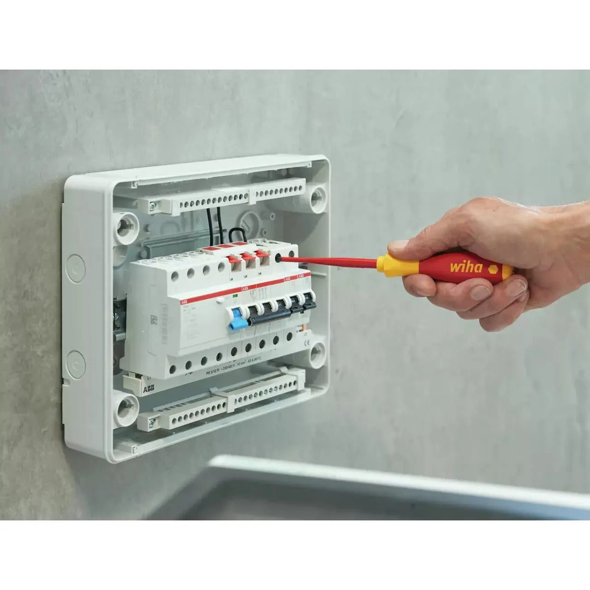 Slotted & Pozidriv – A person uses an insulated screwdriver on an electrical panel