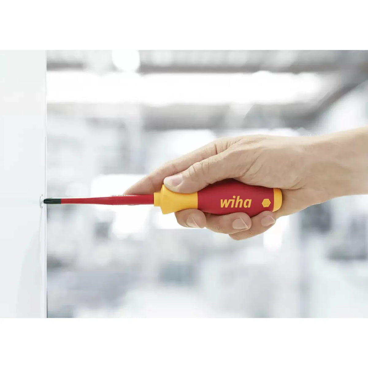 Slotted & Pozidriv – A hand using a red and yellow insulated screwdriver on a screw