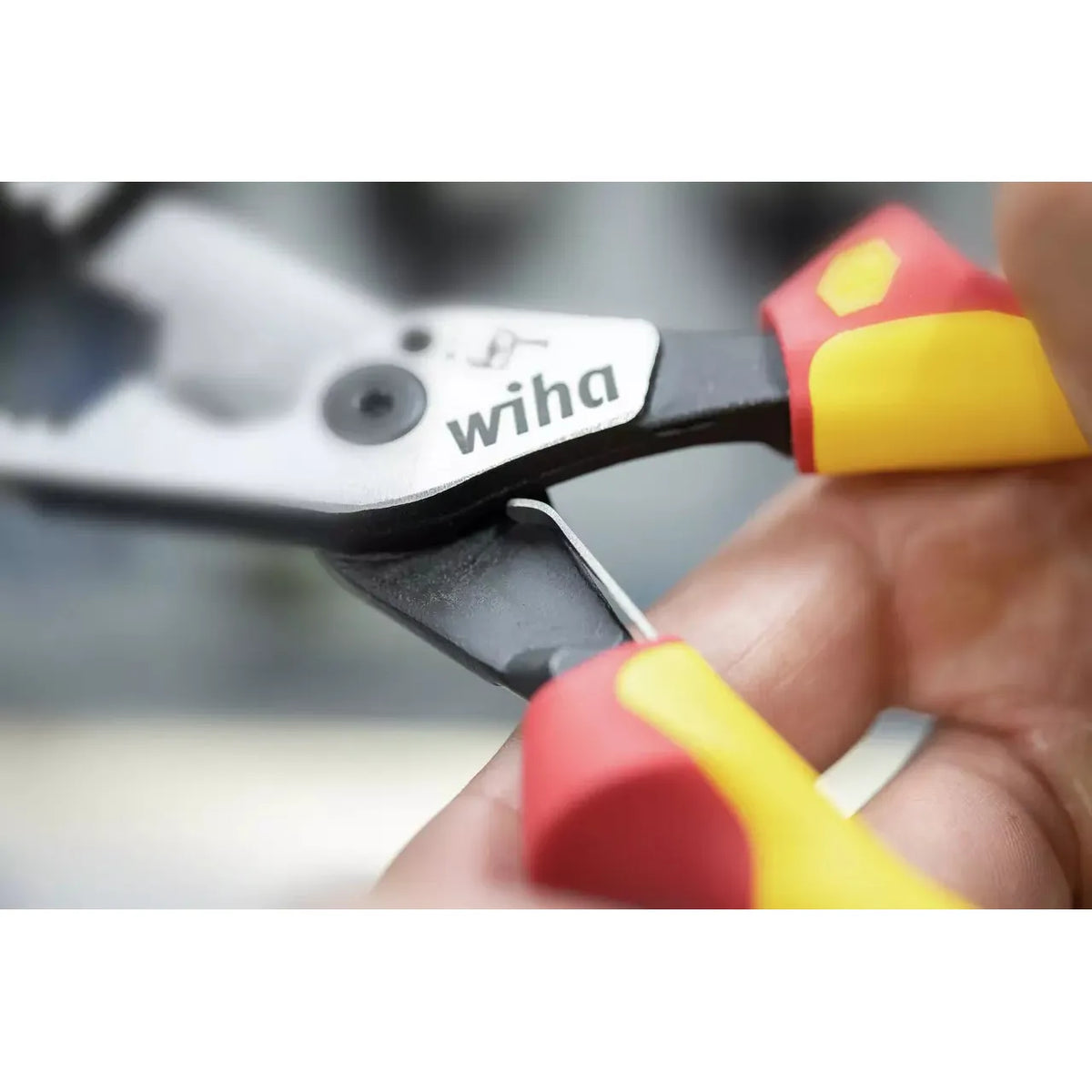 Pliers with yellow and red handles, held in hand during use.