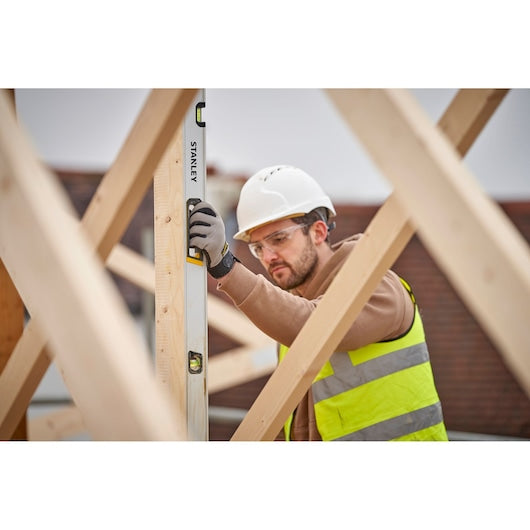 STANLEY FMHT43678-1 spirit level used by worker in safety gear on construction site, vertical view.