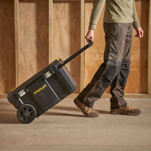 Photo of a STANLEY STST1-80150 rolling tool box being pulled by a person on a construction site.