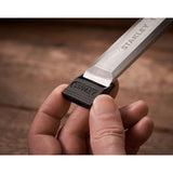 Photo of STANLEY 0-16-130 chisel with black end cap, held in hand, close-up showing detail of blade and handle.