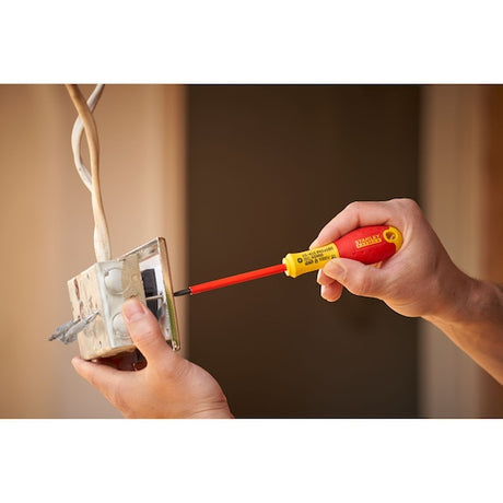 STANLEY 0-65-415 insulated screwdriver with red and yellow handle used for electrical work on a wall switch.