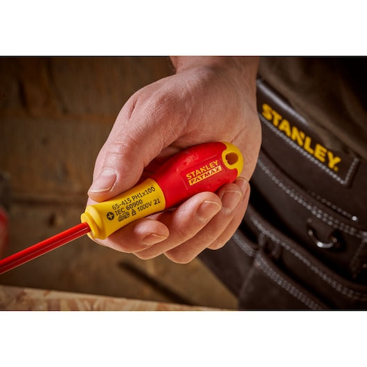Photo of STANLEY 0-65-415 insulated screwdriver with red and yellow handle, held in hand, close-up view.