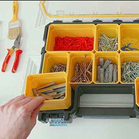 STANLEY 1-97-518 organizer photography, open box showing assorted screws, nails, and wall plugs in yellow compartments, top view.