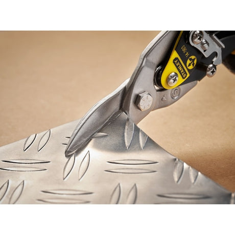 STANLEY 2-14-563 aviation snip cutting patterned metal sheet, close-up angle.