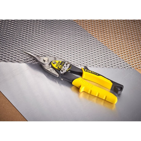 STANLEY 2-14-563 aviation snip with yellow handle on metal mesh and sheet, angled view.