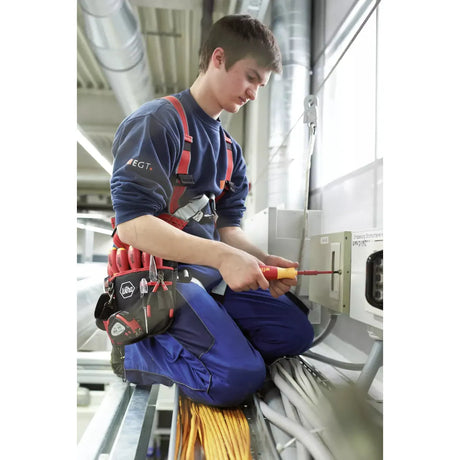 A person is working with an electric screwdriver on a control cabinet.