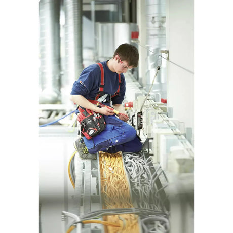 A person working with electrical cables, using a screwdriver, in an industrial setting.