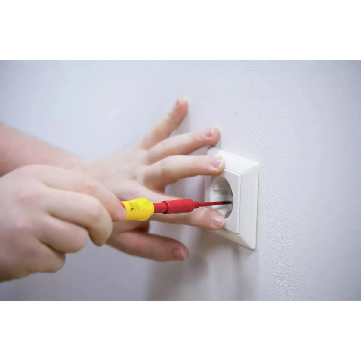 10-piece – Slotted, Phillips & Pozidriv – Person using a red and yellow screwdriver on a wall socket