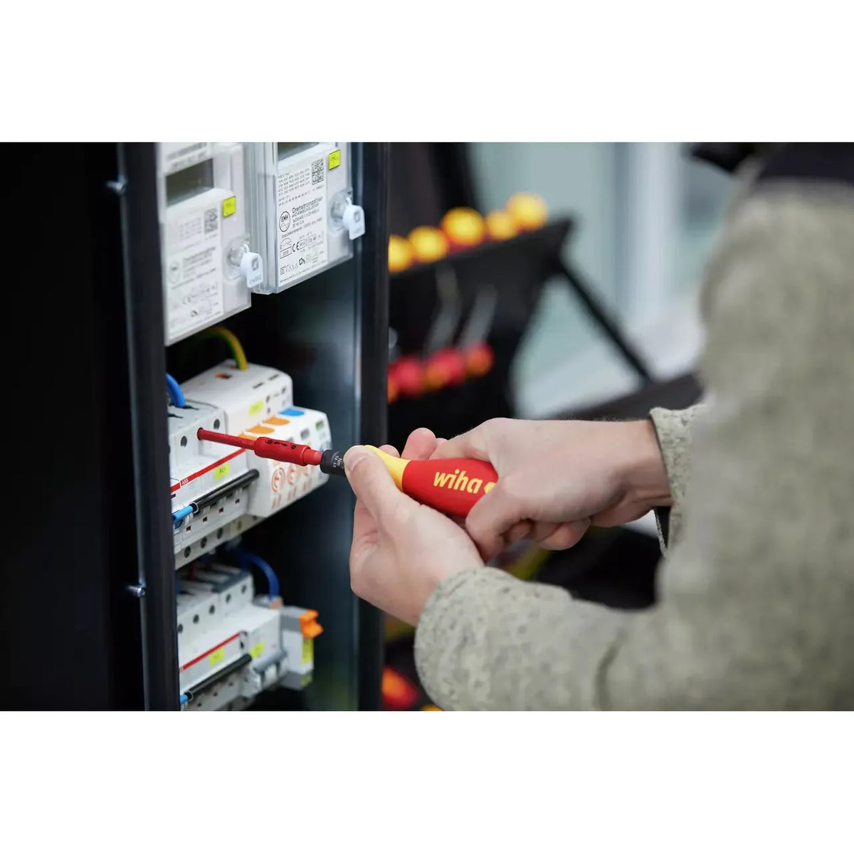 5-piece – Person using an electric screwdriver on an electrical panel