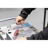 A person uses a red-handled tool on a metal surface