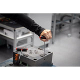 A person uses a hex key with a red and black handle on a metal fixture.