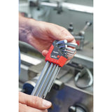 A person holds an ErgoStar hex key set with a red holder in a workshop.