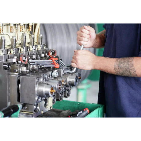 Person using a wrench on industrial machinery with tools nearby.