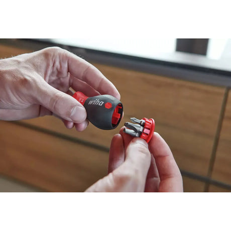 Phillips & Pozidriv – Two hands holding a screwdriver handle and a bit holder with multiple bits. The handle is black and red.
