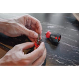 Phillips & Pozidriv – Hands holding a red bit holder with screwdriver bits, next to a black and red screwdriver handle on a table.