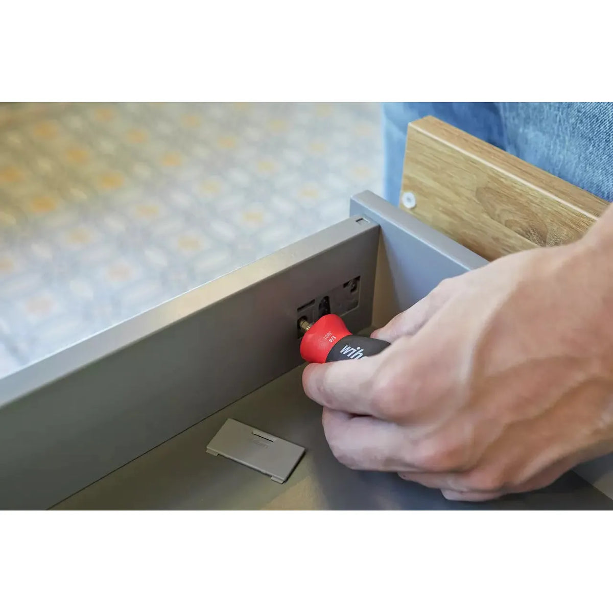 Phillips & Pozidriv – Person using a red-handled screwdriver on a drawer