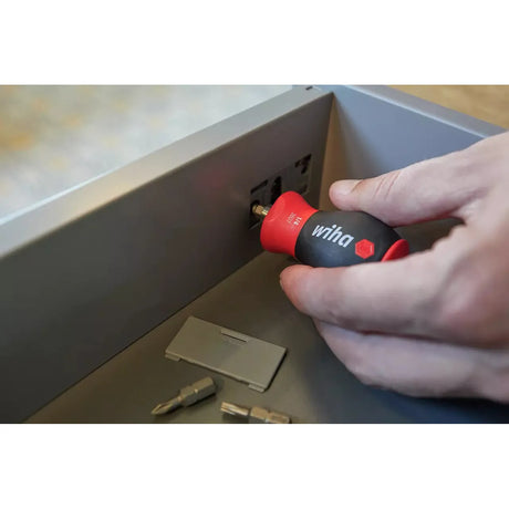 Phillips & Pozidriv – A person uses a red and black screwdriver on a drawer. Bits are placed nearby.