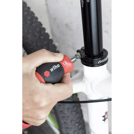 Phillips & Pozidriv – A person uses a red and black screwdriver on a bicycle seat post clamp.