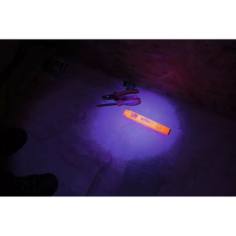 An orange folding ruler and tools on a dimly lit floor.