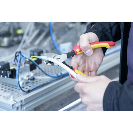 Person using industrial electric cable cutter on white cable