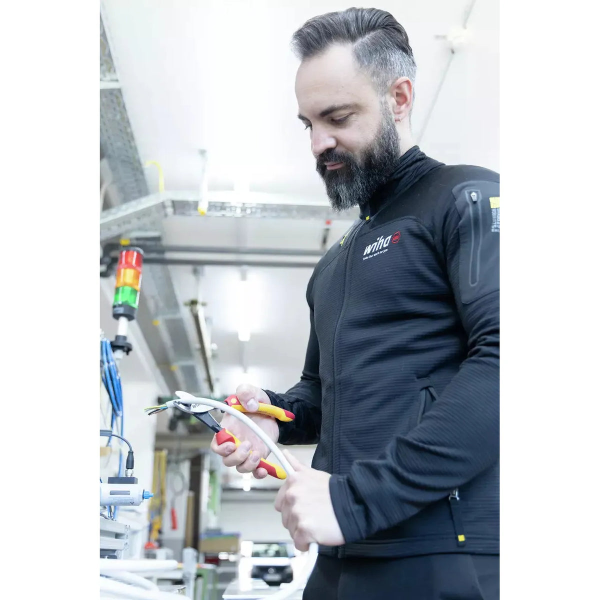 A person using an electric cable cutter on a thick cable in a workshop.