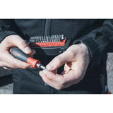 Person holding a screwdriver handle and a bit set in a black and red case
