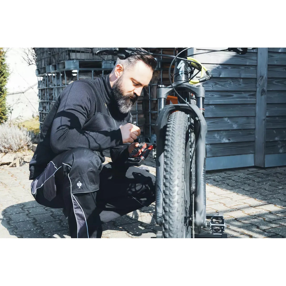 A person is working on a bicycle using a tool kit outdoors.
