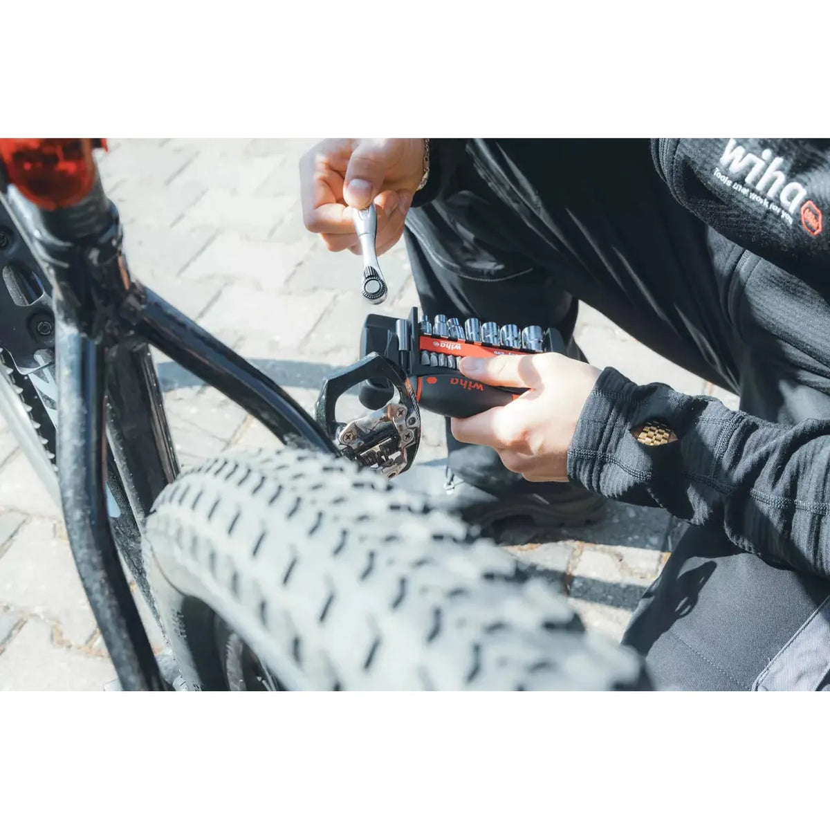 Person using a ratchet wrench on a bicycle pedal