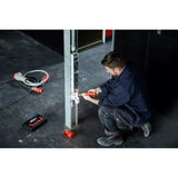 A man works with an electric screwdriver on an outlet on a metal post.