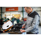 Two people working in a workshop with an electric screwdriver and a device cover.