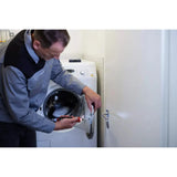 Person repairing washing machine door with electric screwdriver.