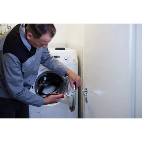 Person repairing washing machine door with electric screwdriver.