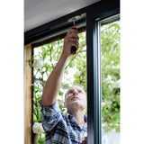 A person adjusts a window with a screwdriver.