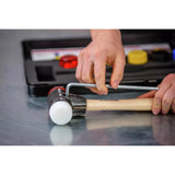 A person adjusts a mallet with a hex key on a metal surface.