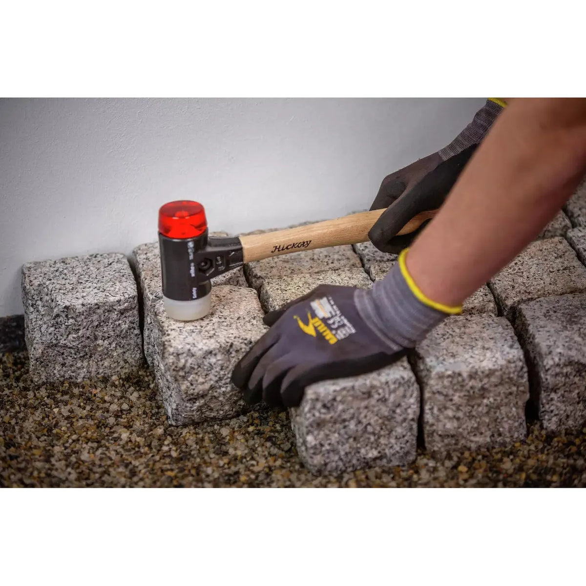 Person using a mallet to adjust paving stones